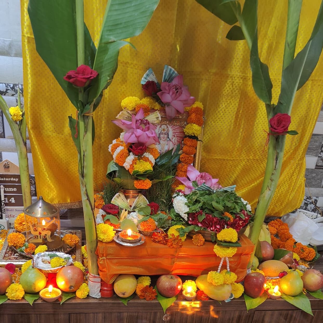 Satyanarayan Puja setup with kalash, banana leaves, flowers and prasad